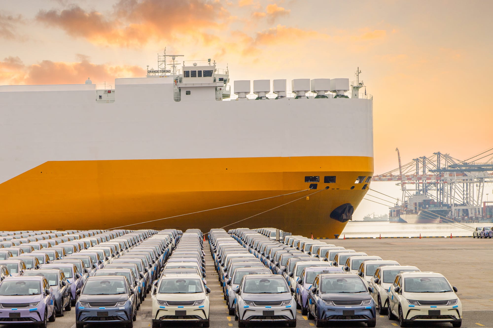 Rows of cars on the quayside beside a RoRo car carrier ship